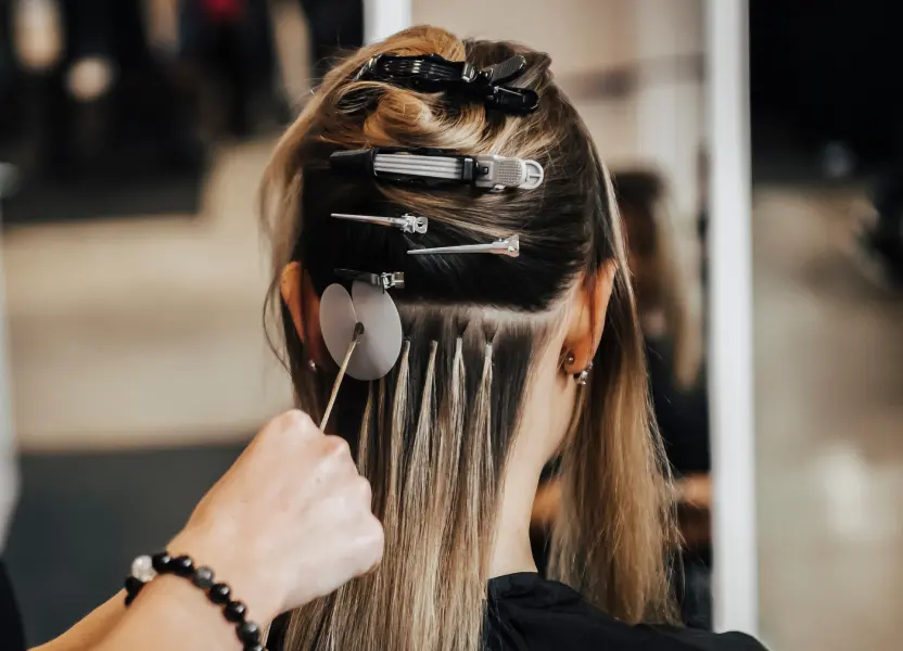 Friseurin klammert Haarpartien ab für eine Strähnchenbehandlung.