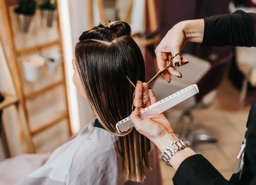 Haare schneiden bei einer Kundin mit gescheiteltem und abgeteiltem Haar.