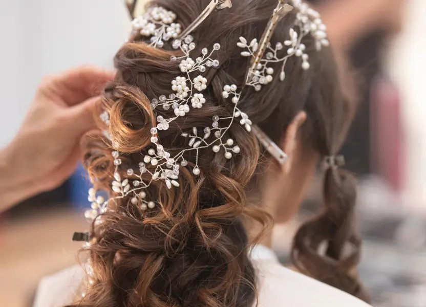 Brautfrisur wird mit dekorativen Blüten und Perlen verziert.