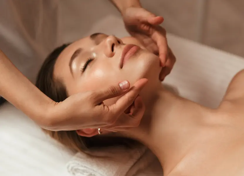 Gesichtsmassage bei einer entspannten Kundin in einem Wellness-Salon.
